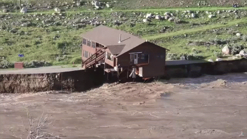 A House Sits In The Middle Of A River Surrounded By Grass And Rocks GIF