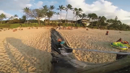 A Jet Ski Is Going Down A Slide On A Beach GIF
