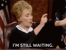 A Judge Is Sitting At A Table In A Courtroom And Says `` I 'M Still Waiting '' . GIF