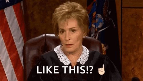 A Judge Is Sitting In A Courtroom With An American Flag In The Background . GIF