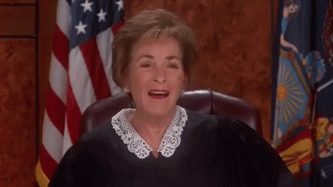 A Judge Is Sitting In Front Of An American Flag And Smiling . GIF