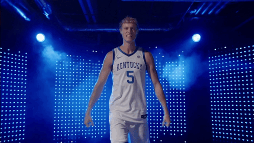a kentucky basketball player stands in front of a blue backdrop