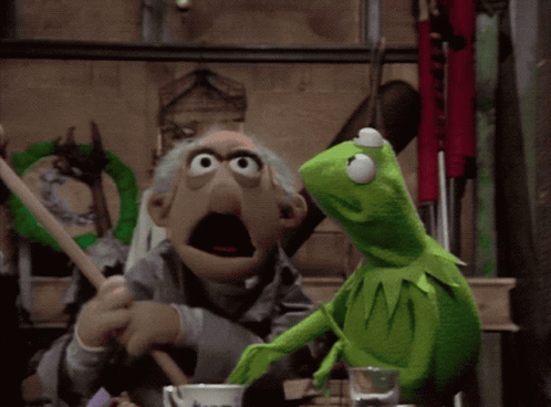 A Kermit The Frog Is Standing Next To An Old Man In A Room GIF