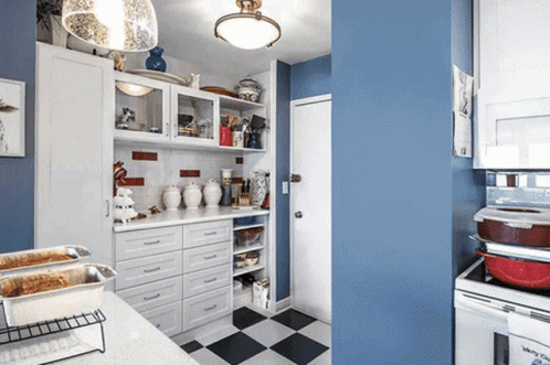 a kitchen with blue walls and white cabinets has a checkered floor