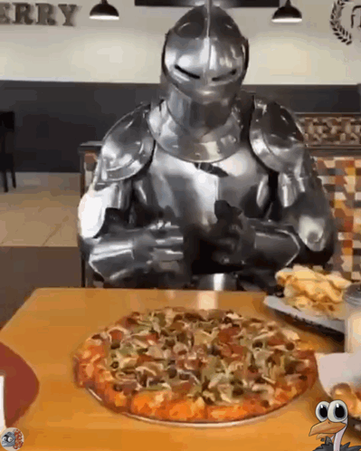 A Knight In Armor Is Sitting At A Table With A Pizza GIF