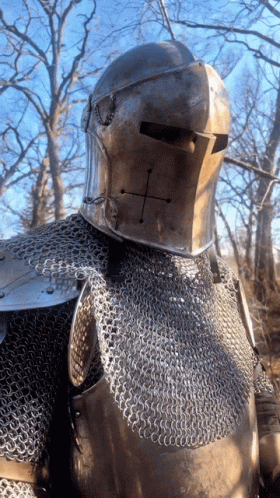 A Knight Wearing Chain Mail And A Helmet With A Cross On His Face GIF