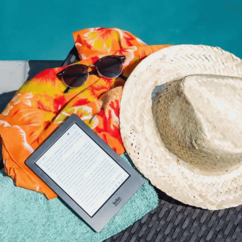 A Kobo Device Is Laying On A Beach Towel Next To A Hat And Sunglasses GIF