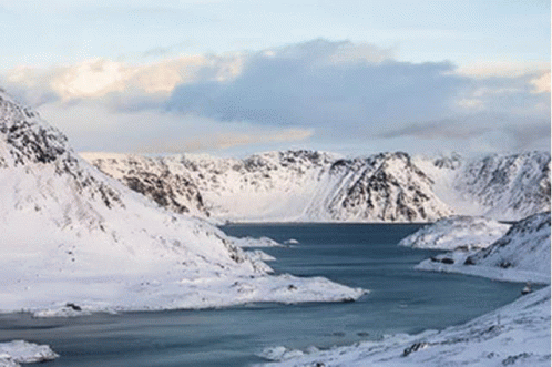 A Lake Surrounded By Snow Covered Mountains With A Blue Sky In The Background GIF
