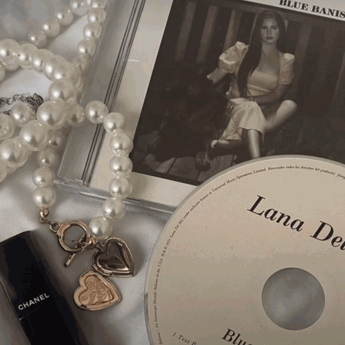 A Lana Del Rey Cd Sits On Top Of A Pearl Necklace GIF