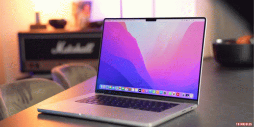 A Laptop Is Open On A Table With A Marshall Speaker Behind It GIF
