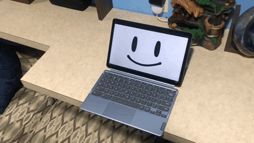 A Laptop With A Smiley Face On The Screen Sits On A Desk GIF