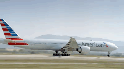 A Large American Airlines Plane Is Taking Off From A Runway GIF