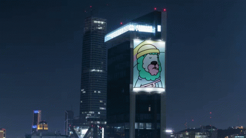 A Large Billboard On The Side Of A Building Has A Picture Of A Man With A Beard And Hat On It GIF