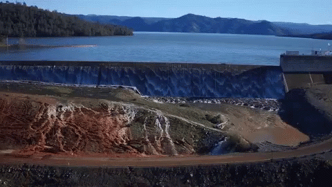 A Large Body Of Water With Mountains In The Background And A Dam In The Foreground GIF