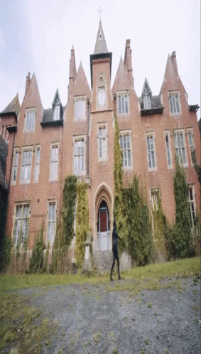 A Large Brick Building With A Clock On The Front GIF