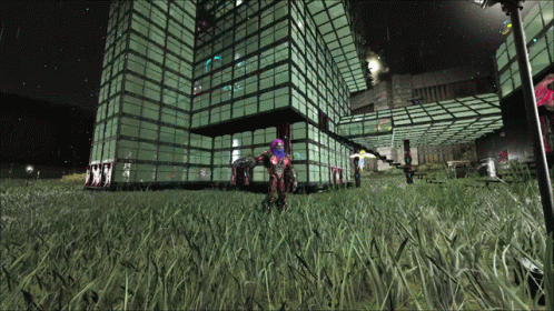 A Large Building With A Lot Of Windows Is Lit Up At Night And A Person Is Standing In Front Of It GIF