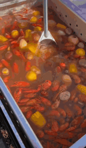 A Large Container Filled With Crawfish , Corn , Potatoes , And A Shovel . GIF