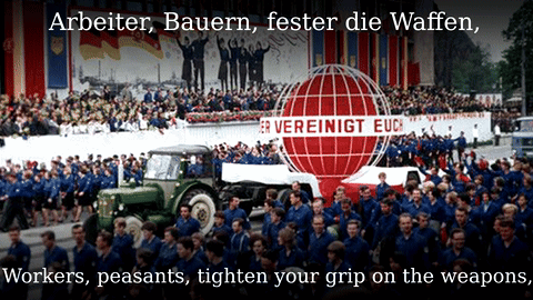 A Large Crowd Of People Are Gathered In Front Of A Sign That Says " Arbeiter Bauern Fester Die Waffen " GIF