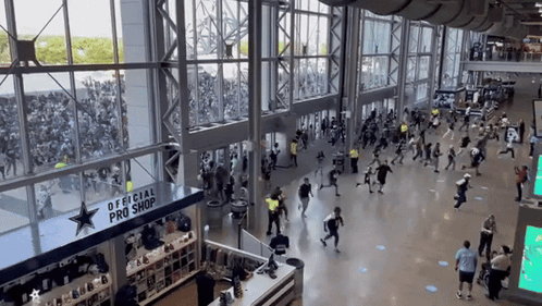 A Large Crowd Of People Are Gathered In Front Of An Official Pro Shop GIF