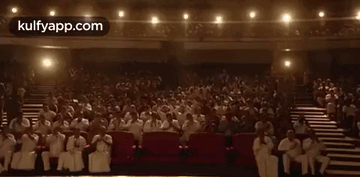A Large Crowd Of People Are Sitting In A Theater . GIF