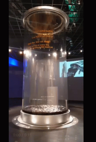 A Large Glass Cylinder With A Sign That Says " See For The Oil Deep " GIF