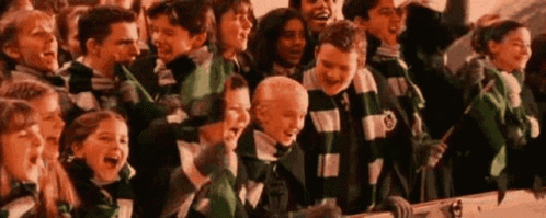A Large Group Of Children Wearing Green And White Scarves Are Standing Next To Each Other . GIF