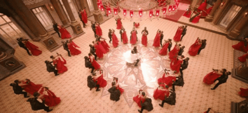 A Large Group Of People Are Dancing In A Room With A Chandelier GIF
