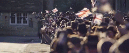 A Large Group Of People Are Standing In Front Of A Building GIF