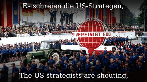 A Large Group Of People Marching In Front Of A Sign That Says Vereinigt Euc GIF