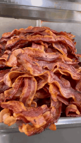 A Large Pile Of Bacon Is Sitting On A Tray GIF