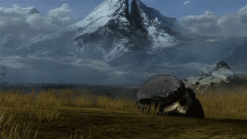A Large Rock In The Middle Of A Field With A Mountain In The Background GIF