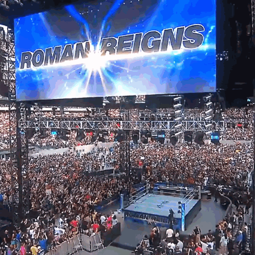 A Large Screen Says Roman Reigns Over A Crowd GIF