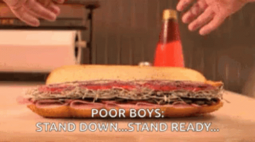 A Large Sub Sandwich Is Sitting On A Wooden Table With The Words `` Poor Boys : Stand Down ... Stand Ready ... '' GIF