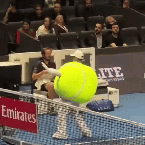 A Large Tennis Ball Is Being Thrown On A Tennis Court With A Sign That Says Emirates On It GIF
