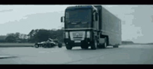 A Large Truck Is Driving Down A Road With A Motorcycle In The Background . GIF