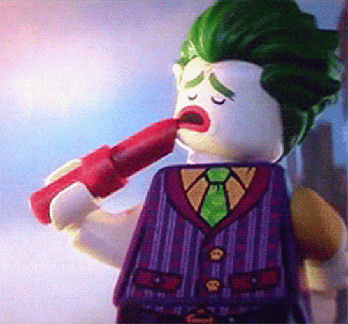A Lego Figure Of The Joker Is Holding A Red Lipstick In His Mouth GIF