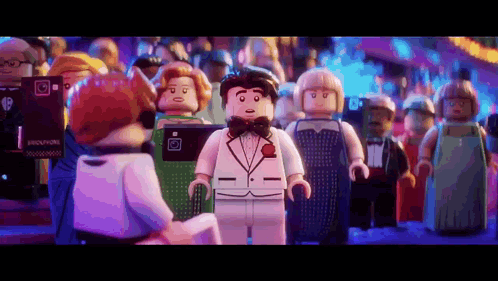 A Lego Man In A Tuxedo Is Standing In Front Of A Crowd Of People . GIF