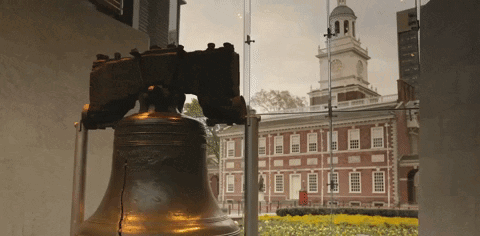 A Liberty Bell Stands In Front Of A Building GIF
