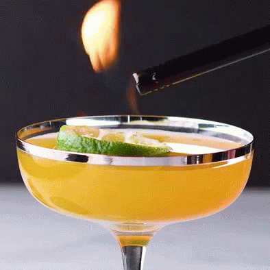 A Lighter Is Being Used To Light A Drink In A Coupe Glass GIF