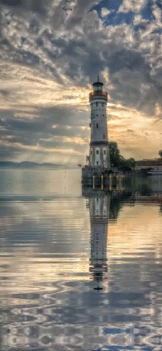 A Lighthouse Stands In The Middle Of A Body Of Water GIF