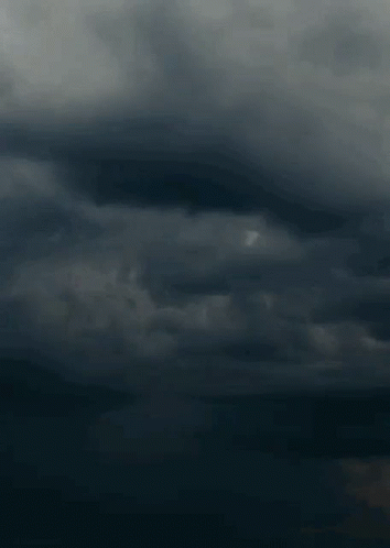 A Lightning Bolt Strikes In A Dark Cloudy Sky . GIF