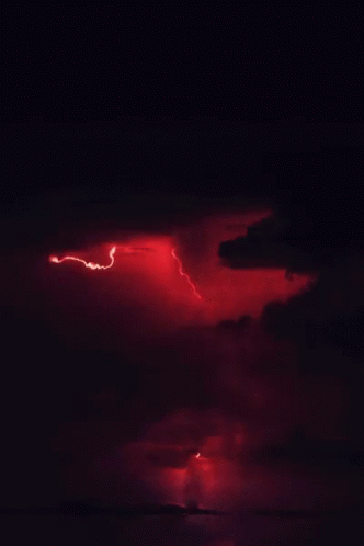 A Lightning Bolt Strikes Through A Cloudy Sky At Night GIF