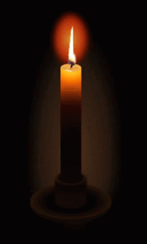 a lit candle in a dark room with a candle holder