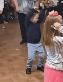 A Little Boy And A Little Girl Are Dancing Together In A Room . GIF