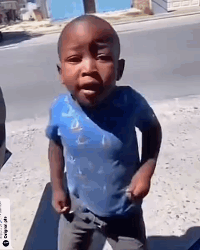 A Little Boy In A Blue Shirt Is Standing On The Sidewalk . GIF