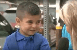 A Little Boy In A Blue Shirt Is Talking To A Woman In A Parking Lot . GIF