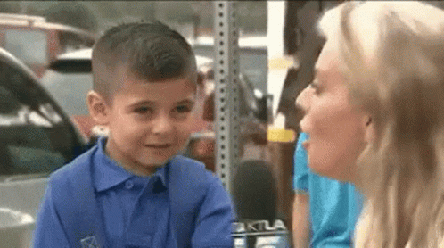 A Little Boy In A Blue Shirt Is Talking To A Woman With A Microphone . GIF