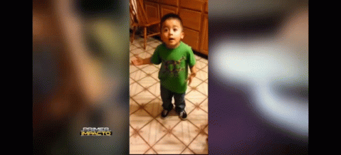 A Little Boy In A Green Shirt Is Standing On A Tiled Floor . GIF