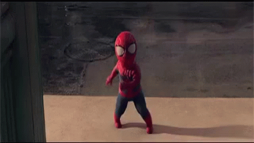 A Little Boy In A Spiderman Costume Is Walking Down The Sidewalk . GIF