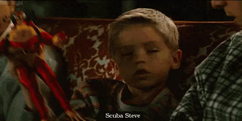 A Little Boy Is Holding A Toy That Says Scuba Steve On It GIF